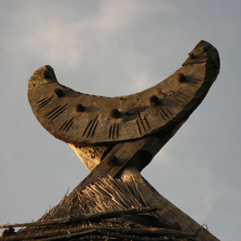 Mondsichel aus geschnitztem Holz als Dachfirst eines alten Reetdachhauses Wechseljahre Naturseminar